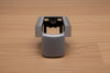 Grey ergonomic spray can adapter, Spray Doctor, on a wooden surface - front perspective view.