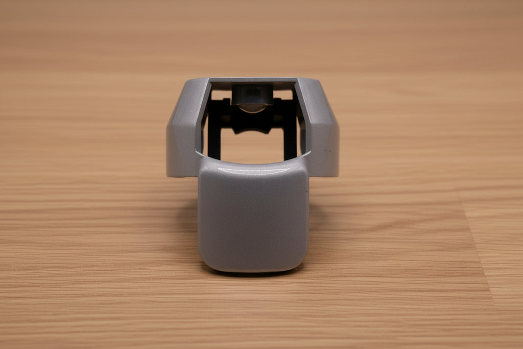 Grey ergonomic spray can adapter, Spray Doctor, on a wooden surface - front perspective view.