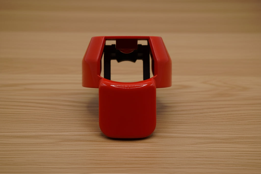 Red ergonomic spray can adapter, Spray Doctor, on a wooden surface - front perspective view.